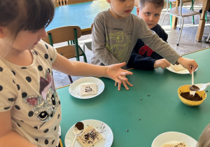 dzieci polewają czekoladą wafle