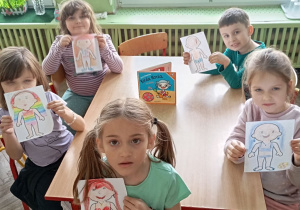 pięcioro dzieci pokazuje swoje prace rysunkowe