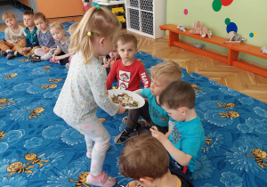 dziewczynka częstuje dzieci czekoladkami