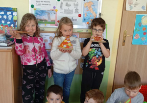 sześcioro dzieci pokazuje jak jedzą pizze
