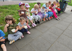 Dzieci siedzą i jedzą lody z kubeczków