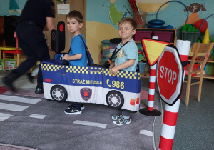 dwoje dzieci w miękkiej atrapie autobusu i autka