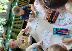 dzieci kolorują kolorowanki przy stoliku