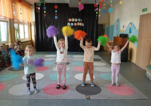 czworo dzieci macha kolorowymi pomponami