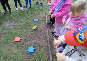 dzieci zwijają sznurek na patyk z drewnianymi żółwiami