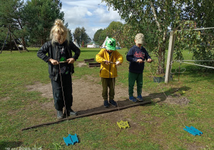 dzieci zwijają sznurek na patyk z drewnianymi żółwiami