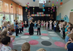 Dzieci w kole a dwie dziewczynki w środku w=z rękoma na własnym karku