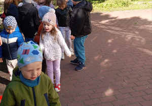 na pierwszym planie chłopiec trzyma łyżkę a na drugim planie dzieci ustawione w rzędzie