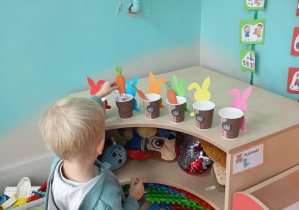 chłopiec wkłada marchewkę do odpowiedniego kubeczka