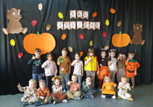 Dzieci pozują do zdjęcia na tle dekoracji jesiennej