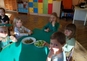 dzieci siedzą przy stoliku i jedzą ogórki