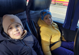 dwoje dzieci siedzi obok siebie w autokarze
