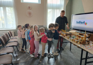 dziewczynki stoją w kolejce przed wystawa miodów