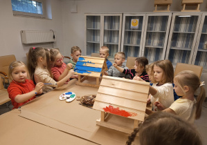 dzieci malują 2 karmniki- jeden na czerwono, drugi na niebiesko