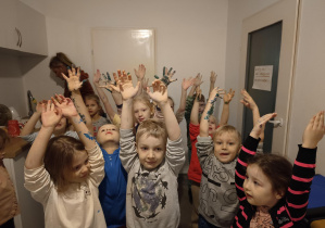 grupa dzieci unosi ręce wysoko