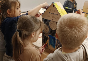 dzieci malują drewniany domek dla pszczół