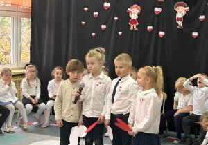 dzieci ubrane w galowe stroje recytują wiersze