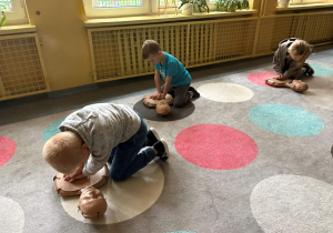 dzieci ćwiczą resuscytacje na fantomie