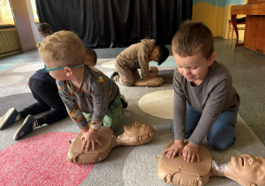 dzieci ćwiczą resuscytacje na fantomie