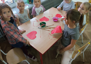 dziewczynki siedzące przy stole z pomalowanymi sercami