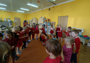 dzieci stoją w kole i podają sobie piłki