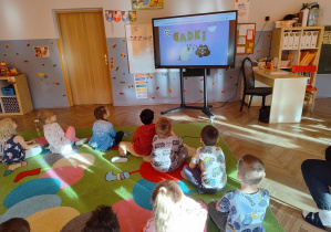 dzieci oglądają na ekranie animacje edukacyjną