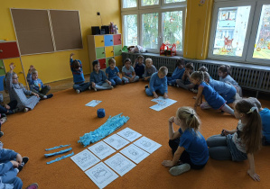 Chłopiec składa obrazek w całość a reszta dzieci przygląda się