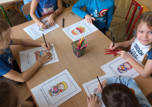 Dzieci kolorują przy stolikach kolorowanki