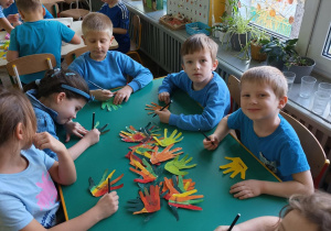 Dzieci podpisują kolorowe rączki wykonane z papieru i pokolorowane