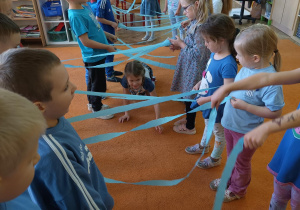 Dzieci tworzą most z niebieskiej bibuły a jedna dziewczynka przechodzi