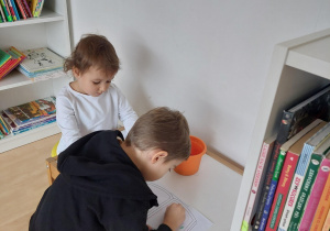 dwoje dzieci siedzi przy stoliku i koloruje