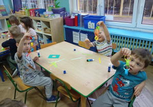 Dzieci przy stole pokazują łańcuch papierowy