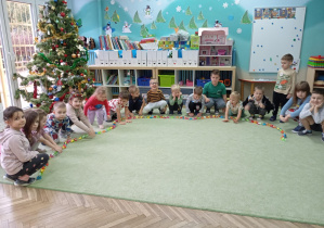 grupa dzieci kuca i prezentuje wspólny długi łańcuch papierowy