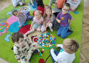 Dzieci z siedzą wokół własnej mandali z klocków