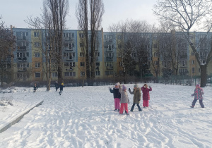Grupa dzieci bawią się na śniegu.