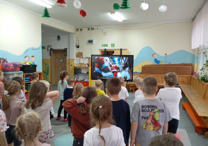 grupa dzieci ćwiczy skłony przed ekranem