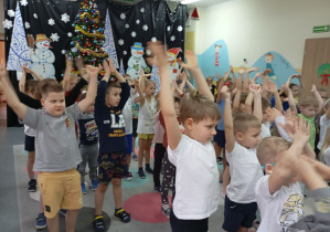 grupa dzieci unosi ręce nd głową