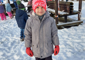 chłopiec na śniegu a za nim drewniany pociąg