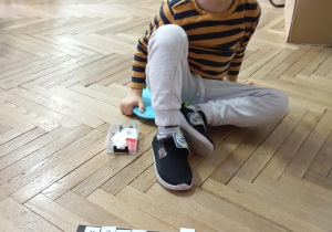 chłopiec siedzi na podłodze, przed nim leży mata z literkami