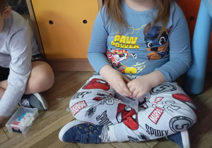 chłopiec siedzi na podłodze, przed nim leży mata z literkami