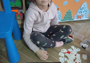 dziewczynka siedzi na podłodze. Przed nią na podłodze le