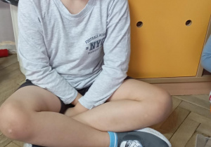 chłopiec siedzi na podłodze, przed nim leży mata z literkami