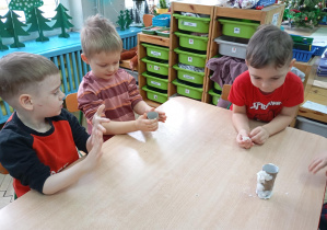 dzieci siedzą przy stole i wykonują karmniki