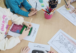 dzieci wykonują karty pracy przy stolikach