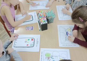 dzieci wykonują karty pracy przy stolikach