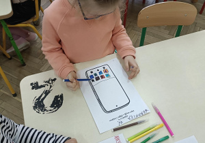 dzieci wykonują karty pracy przy stolikach