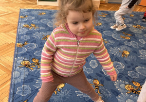 dziewczynka stoi w rozkroku na dywanie