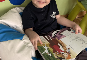 chłopiec siedzi i ogląda książeczkę