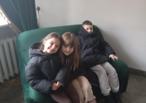 Troje dzieci siedzi na fotelu