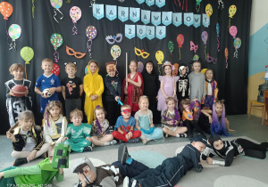 Grupa dzieci pozuje do zdjęcia na tle dekoracji karnawałowej